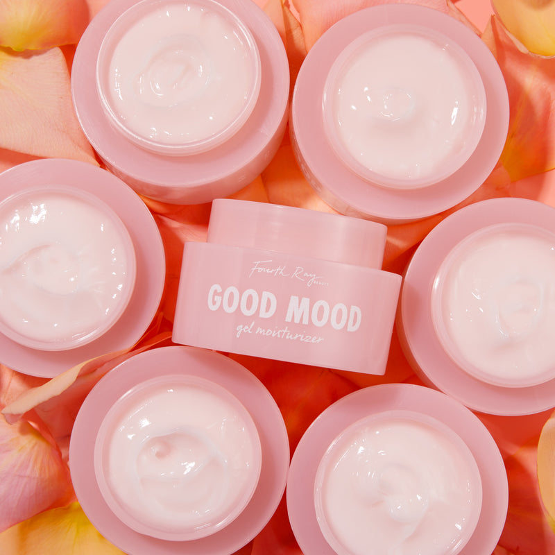 Good Mood gel moisturizer , with multiple good mood products surrounding it; in front of pink/orange  rose petals 